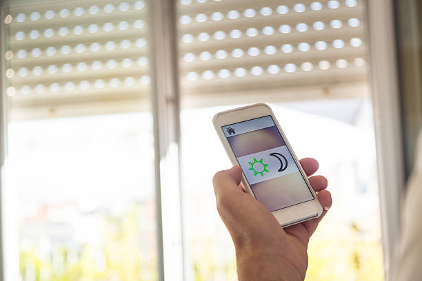 Smart home: man controlling blinds with app on his phone stock photo