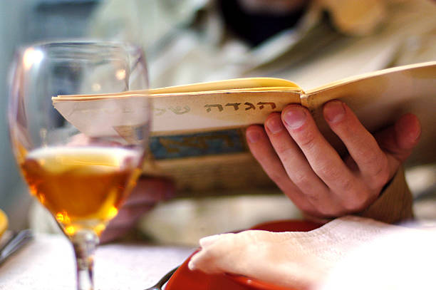 Passover Dinner Man reads in the Haggadah book during Passover Seder dinner. passover celebration stock pictures, royalty-free photos & images