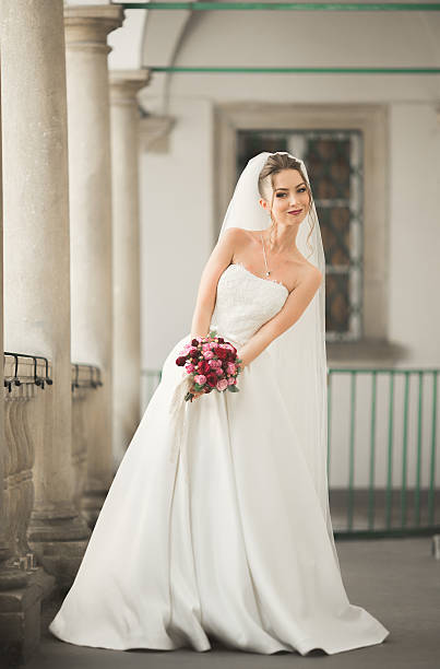istock Beautiful bride with wedding bouquet posing in old city 601384472