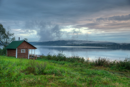 Vintage Russian smoke sauna log cabin on a river shore.
