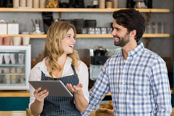 istock Smiling man and waitress standing at counter using digital tablet 601388126
