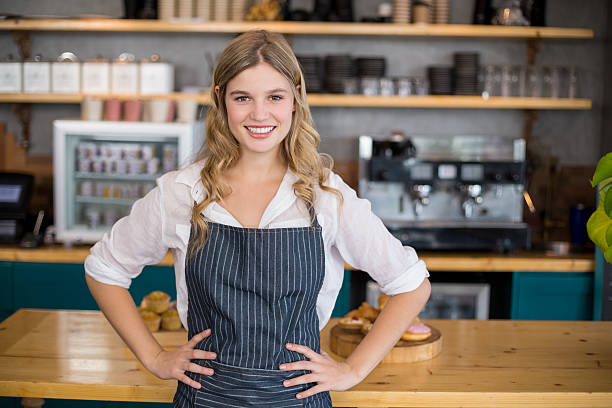 istock Portrait of smiling waitress standing with hands on hip 601388220