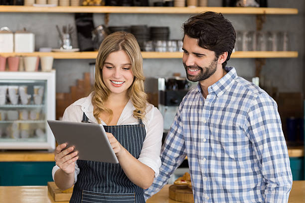 istock Smiling man and waitress standing at counter using digital tablet 601388822