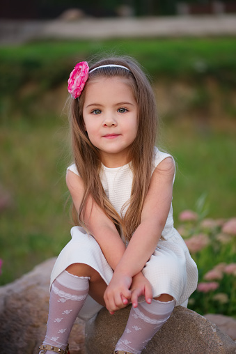 Photo of cute little girl sitting on green grass