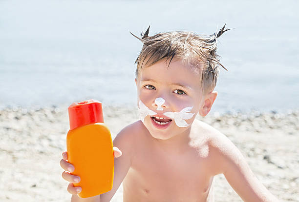 istock Moustaches cat drawing sunscreen (suntan lotion) on boy face. 601390128