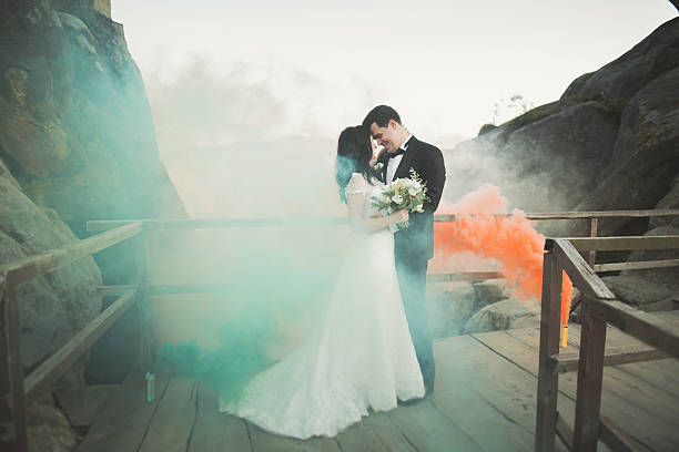 istock Wedding couple posing near rocks with colored smoke behind them 601390684