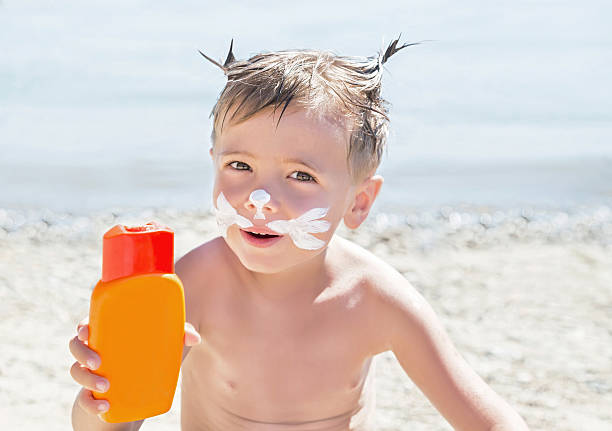 istock Moustaches cat drawing sunscreen (suntan lotion) on boy face. 601391228