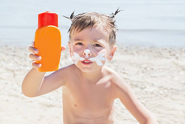 istock Moustaches cat drawing sunscreen (suntan lotion) on boy face. 601391818