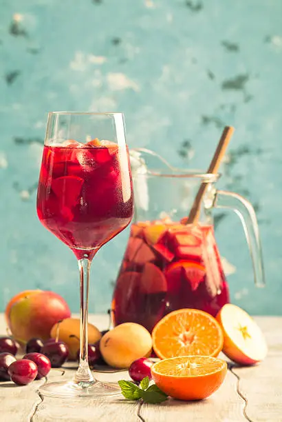 Refreshing sangria or punch with fruits in glass and pincher
