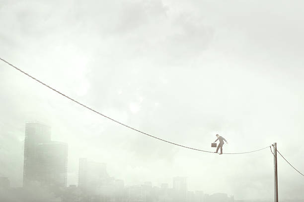 homem de negócios equilibrando em um fio elétrico sobre a cidade - tightrope balance walking rope - fotografias e filmes do acervo