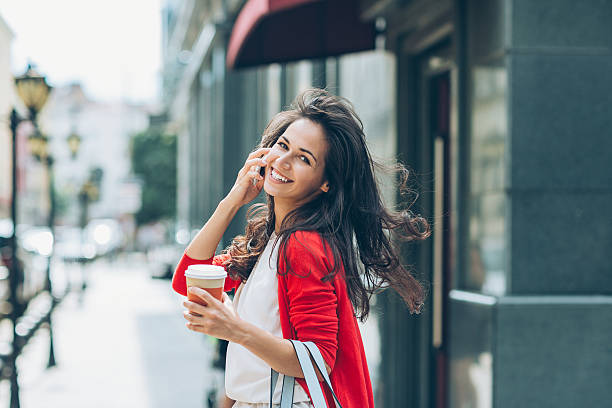 fille joyeuse avec téléphone dans la rue en regardant en arrière - red text messaging cafe teenage girls photos et images de collection
