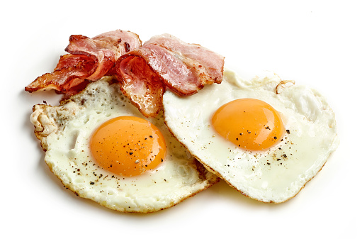 fried eggs and bacon slices isolated on white background