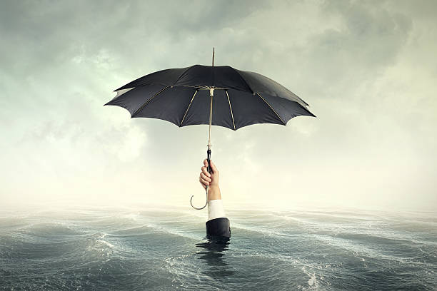 business man with umbrella drawning in the flowd stock photo