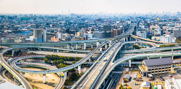Panoramic aerial view over the loops and curves of an urban elevated highway intersection in the heart of downtown Osaka, Japan.