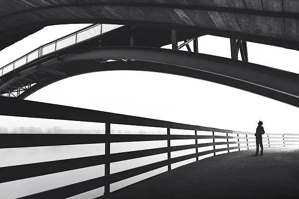 Photo of Man standing under bridge arch