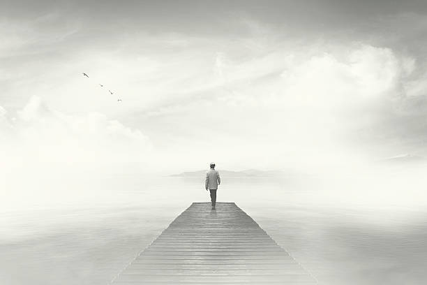 Man walking on a boardwalk in the fog Man walking on a boardwalk in the fog absence photos stock pictures, royalty-free photos & images