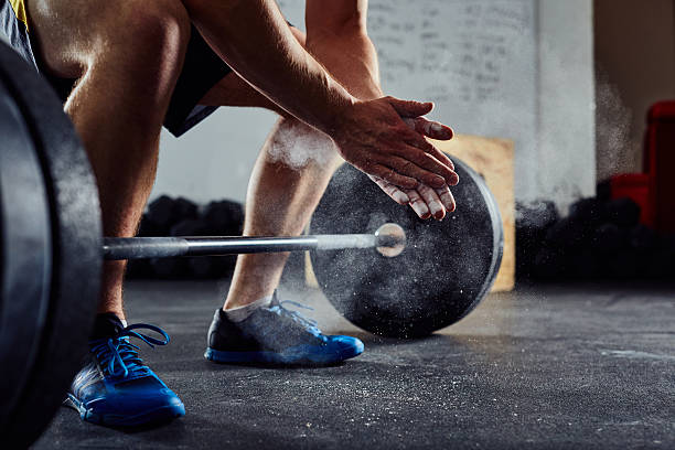 primo piano del sollevatore di pesi che applaude le mani prima dell'allenamento del bilanciere - cross training foto e immagini stock