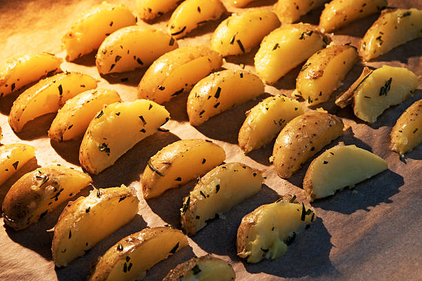 potato wedges with rosemary on baking paper  in the hot oven, selected focus and narrow depth of field