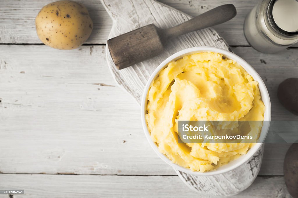 Mashed potatoes in bowl on the white wooden table horizontal Mashed potatoes in the bowl on the white wooden table with  raw potatoes and bottle of milk top view Mash - Food State Stock Photo