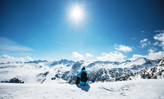 Snowboarder sitting on the edge of the mountain and enjoy the winter landscape. Canillo ski region. Andorra