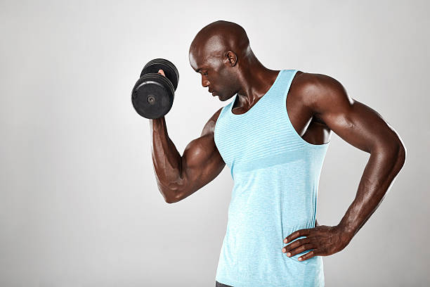 молодой мускулистый человек делает тяжелые упражнения гантели - flexing muscles men human muscle human arm стоковые фото и изображения