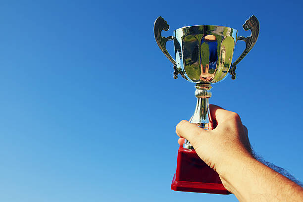 istock Man holding a trophy as a winner against the sky 601912758