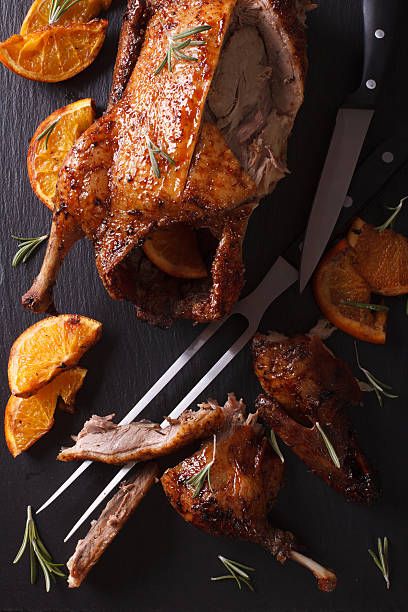 istock Cutting the roast duck and oranges closeup. vertical top view 601912924
