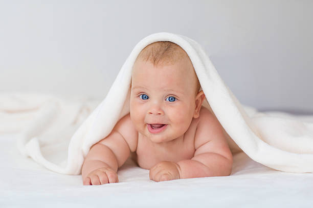 istock Caucasian baby boy covered with  towel joyfully smiles at camera 601913244