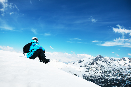 Snowboarder sitting on the edge of the mountain and enjoy the winter landscape. Canillo ski region. Andorra