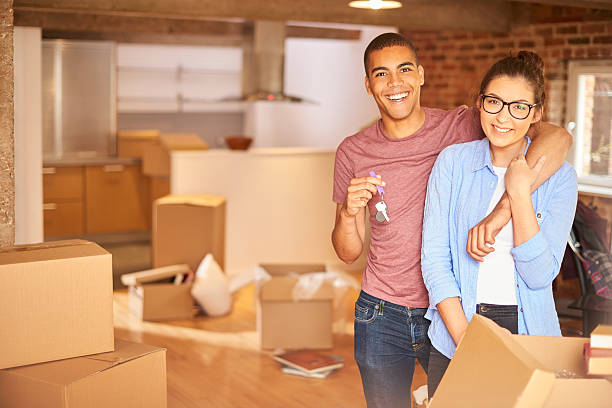 new beginnings a young couple unpack their belongings as they settle into their new loft apartment . They are hugging and looking to camera smiling holding their keys aloft . key package stock pictures, royalty-free photos & images