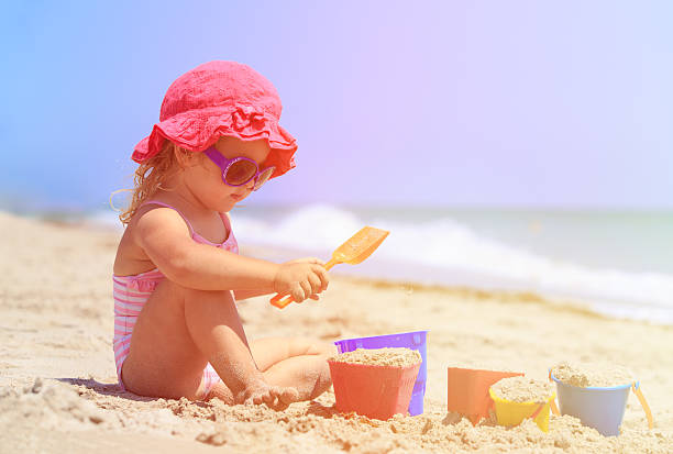 istock cute little girl play with sand on beach 601920804
