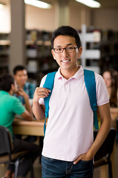 istock Asian male student with a backpack at the library 601923664