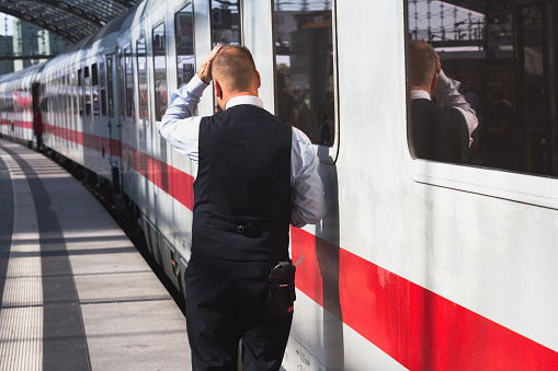 Berlin, Germany - September 9, 2016: Train conductor from behind standing in front of ice train at central station in Berlin.