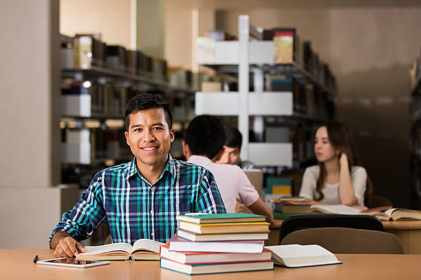 istock Latin college student in the library and smiling at camera 601928420