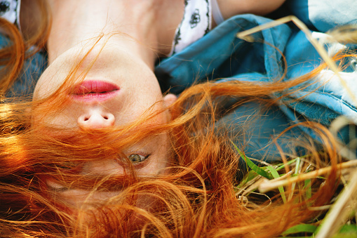 Redhead young girl lying in a meadow
