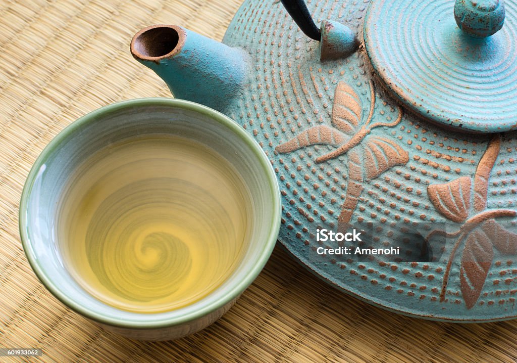 Oriental cast iron tea pot with cup Oriental cast iron tea pot with tea cup on tatami mat Tea - Hot Drink Stock Photo