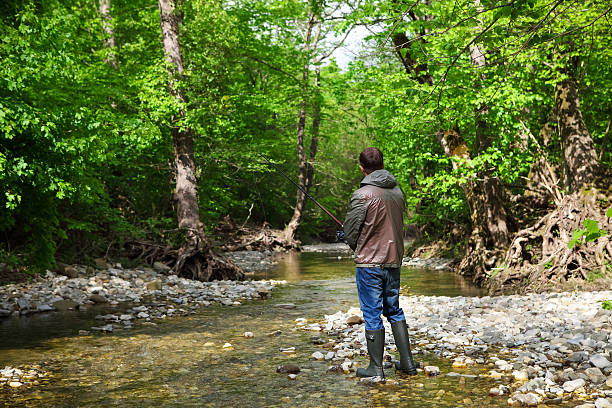 Fisherman with fly-fishing on mountain river. Spring time