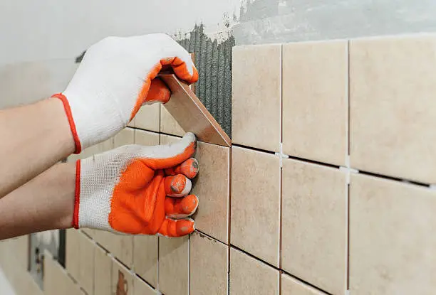 Photo of Worker  putting  tiles on the wall in the kitchen.