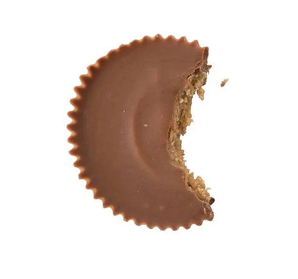 A single chocolate peanut butter cup overhead with a bite taken out of it, isolated on white.