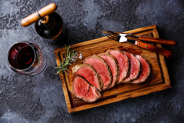 Sliced tenderloin Steak roastbeef and Red wine Sliced grilled tenderloin Steak roastbeef on wooden cutting board and Red wine on dark background beef stock pictures, royalty-free photos & images