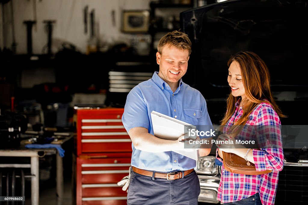 Heureux client discute des réparations avec le mécanicien automobile dans l’atelier de réparation. - Photo de Garage automobile libre de droits