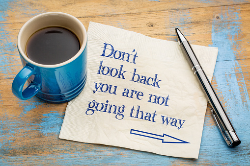 Do not look back  you are not going that way - handwriting on a napkin with a cup of espresso coffee