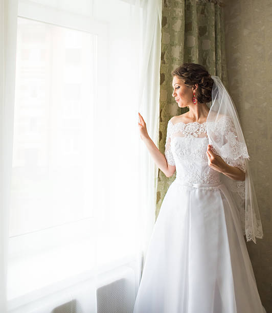 istock beautiful young bride standing beside a window waiting 602288158