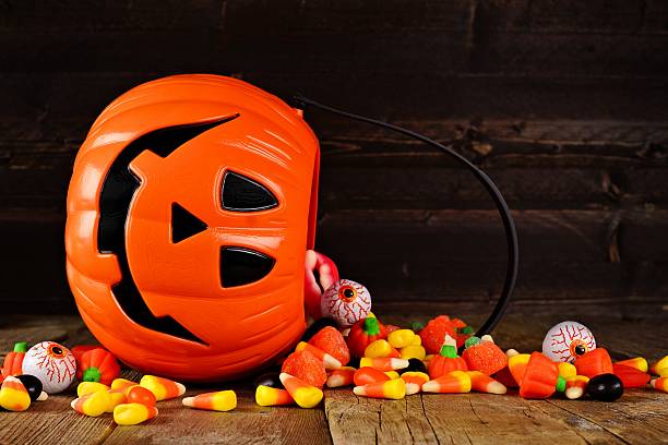 istock Spilling Halloween Jack o Lantern candy pail on wood 602291854