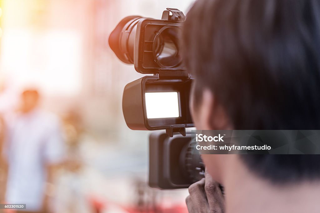 Videographer takes video camera Videographer takes video camera whit white screen and blur image of group people in the background with free copy space for your text Adult Stock Photo
