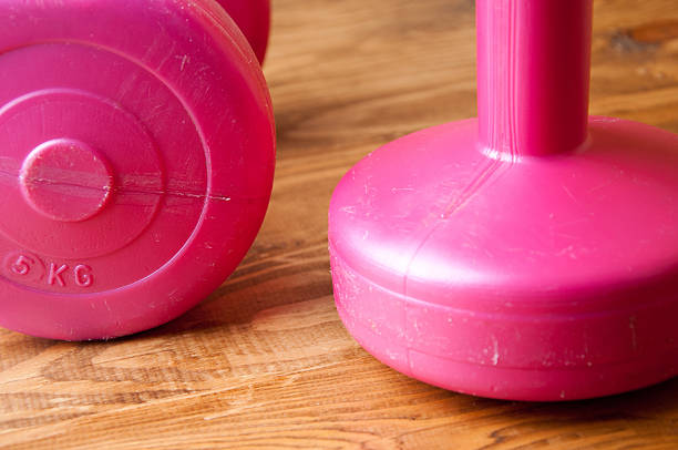 istock Two pink dumbbells on a wooden table 602302398