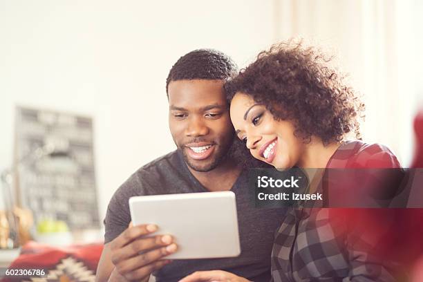 Afro American Happy Couple Using A Digital Tablet At Home Stock Photo - Download Image Now