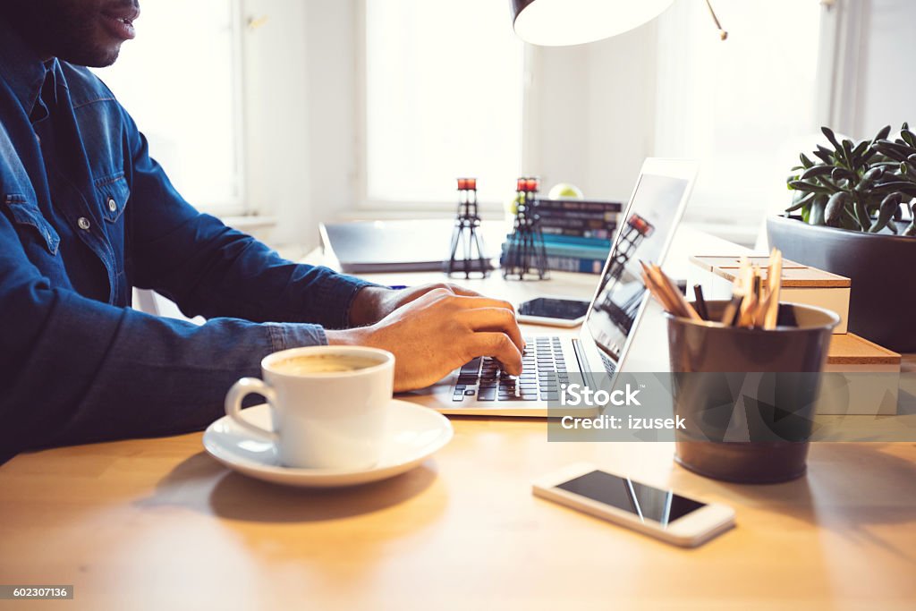 Afro american young man typing on laptop in an office Afro american young man using laptop at home or in the office. Close up of hands. African-American Ethnicity Stock Photo