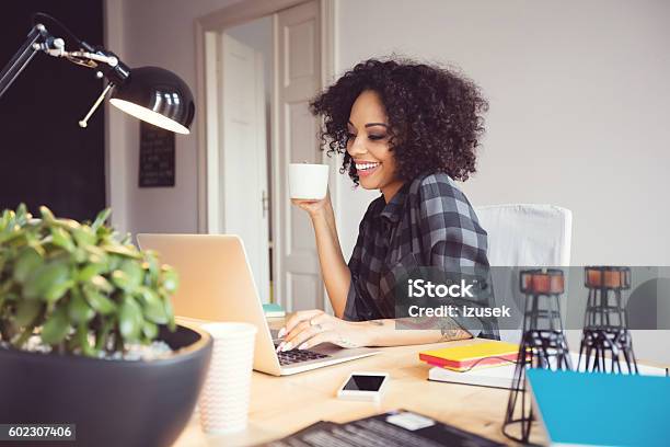 Afro Young Woman In The Home Office Using Laptop Stock Photo - Download Image Now - Working At Home, Home Office, One Woman Only