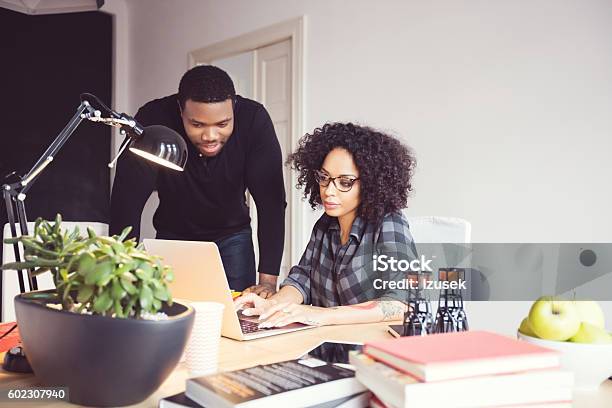 Two Designers In The Office Using Laptop Together Stock Photo - Download Image Now - Using Laptop, Adult, Advice